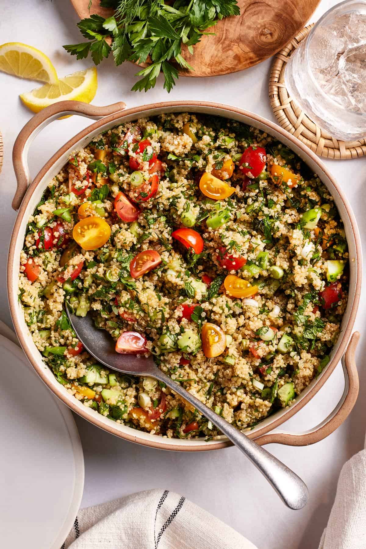 Quinoa tabbouleh in a salad bowl with a spoon on the side.