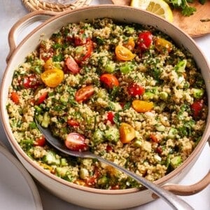 Quinoa tabbouleh in a salad bowl with a spoon on the side.