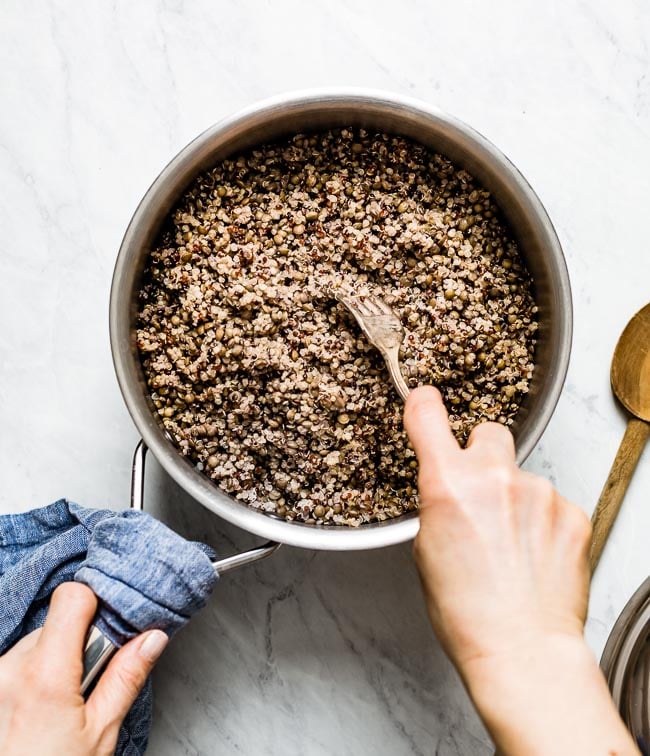 A woman is fluffing quinoa from after it is cooked