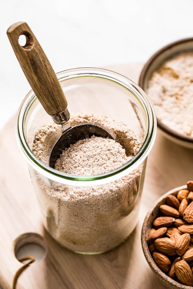 Almond pulp leftover from making almond milk at home is placed in a jar.