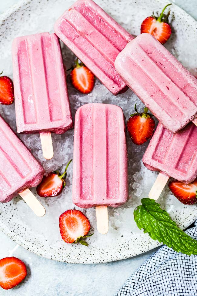 Strawberry Coconut Milk popsicles on a bed of ice with mint leaves