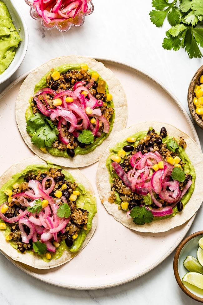 Quinoa Black Bean Tacos topped off with avocado dressing and corn on a plate.