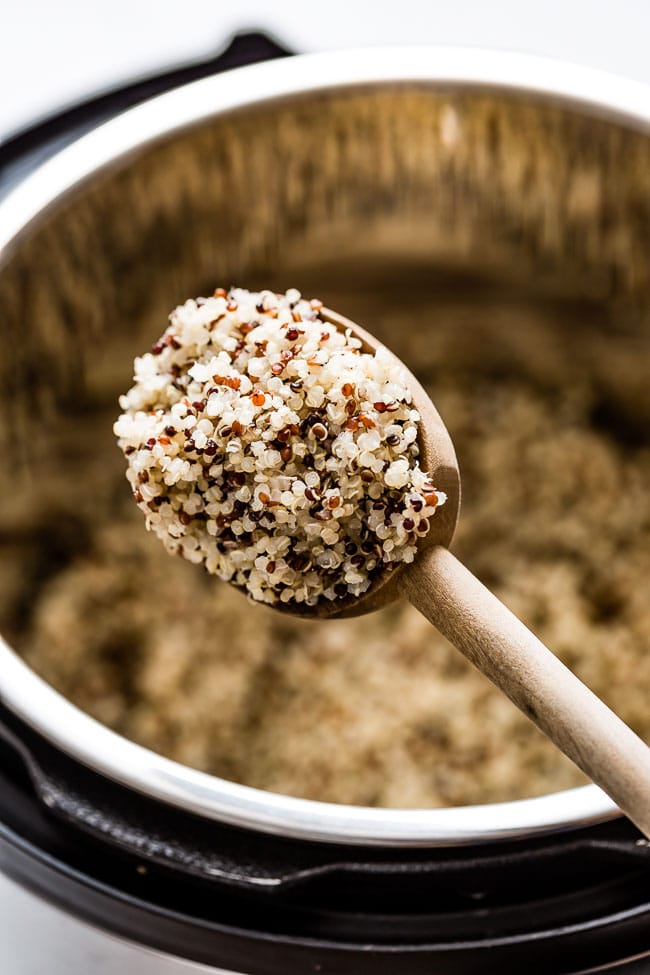 A wooden spoon of tricolor quinoa in instant pot