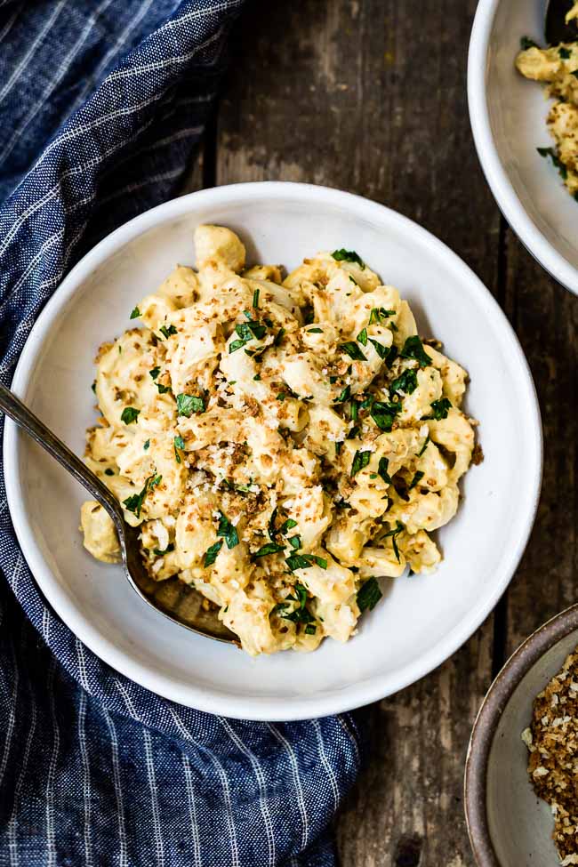 A bowl of homemade vegan mac and cheese recipe is garnished with parsley and breadcrumbs