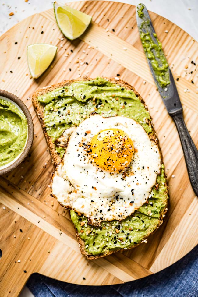 healthy avocado dressing is spread over a piece of toast and topped off with an egg
