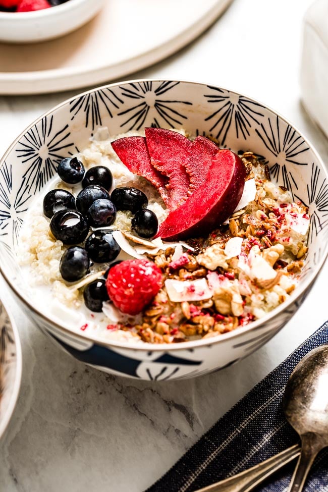 A bowl of Instant Pot Quinoa Breakfast bowl topped off with fresh fruit and nuts.