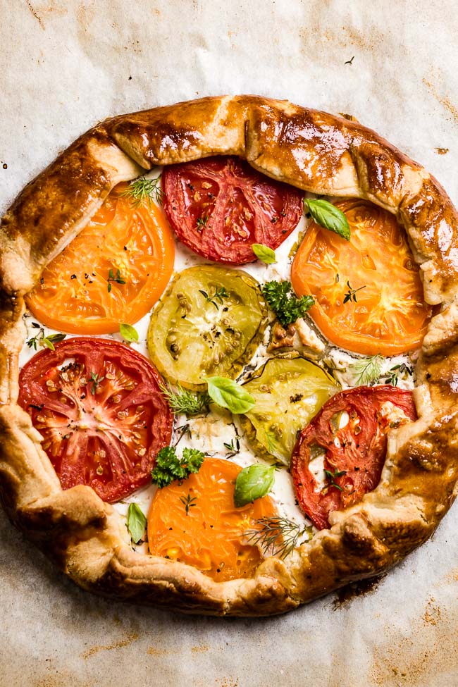 Easy tomato galette fresh out of the oven garnished with herbs from the top view