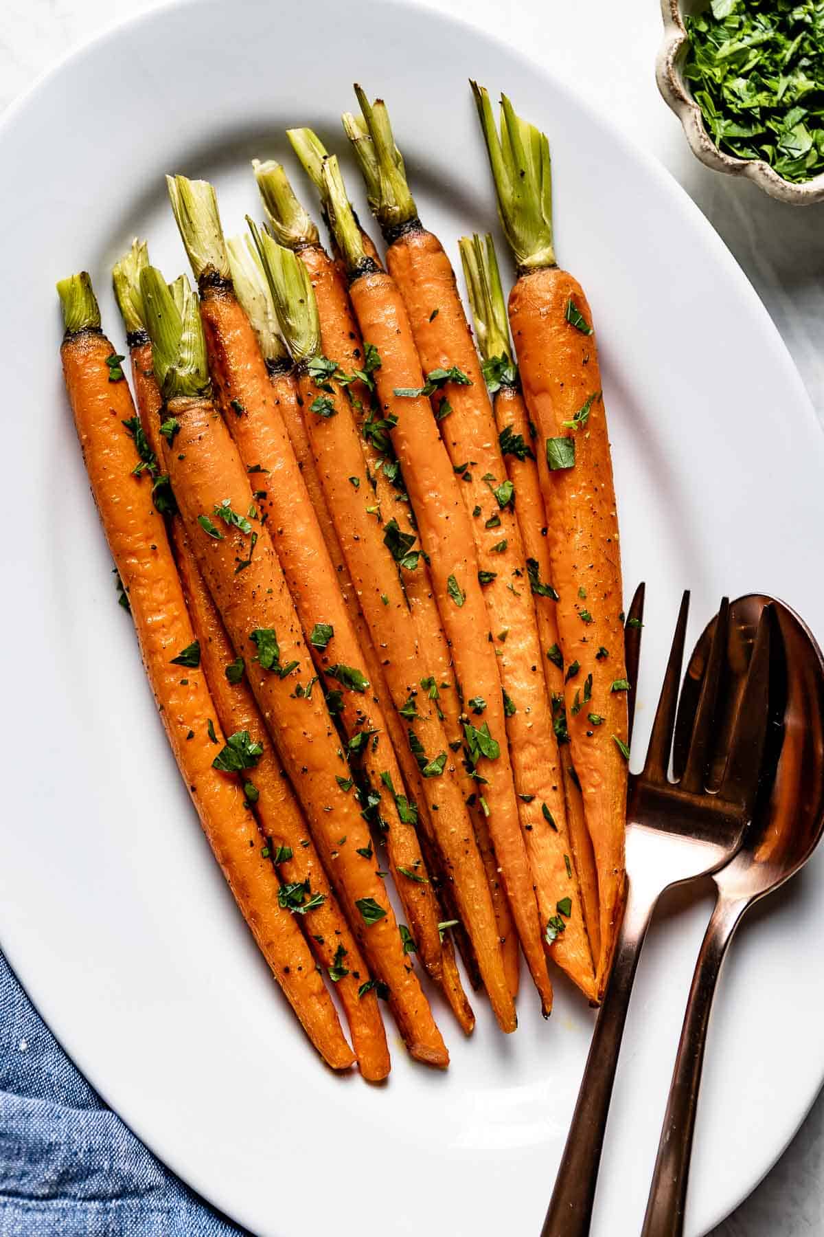 Whole roasted carrots garnished with parsley from the top view.