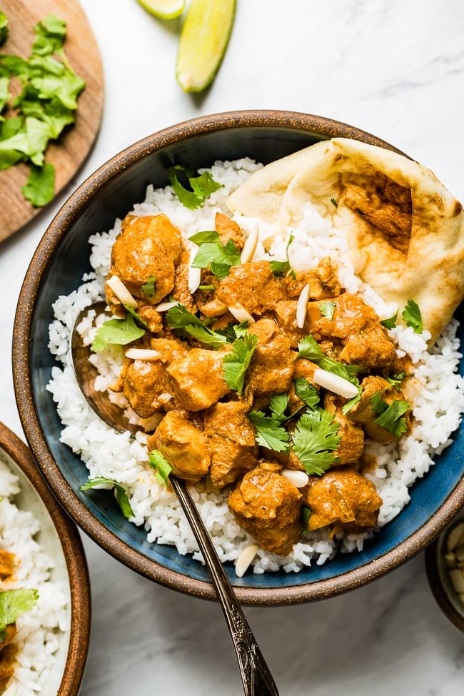 Crockpot Butter Chicken recipe placed in a bowl over basmati rice and naan