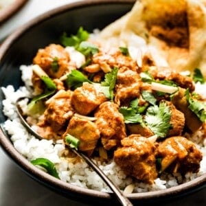 Crock pot butter chicken in a bowl served over rice.