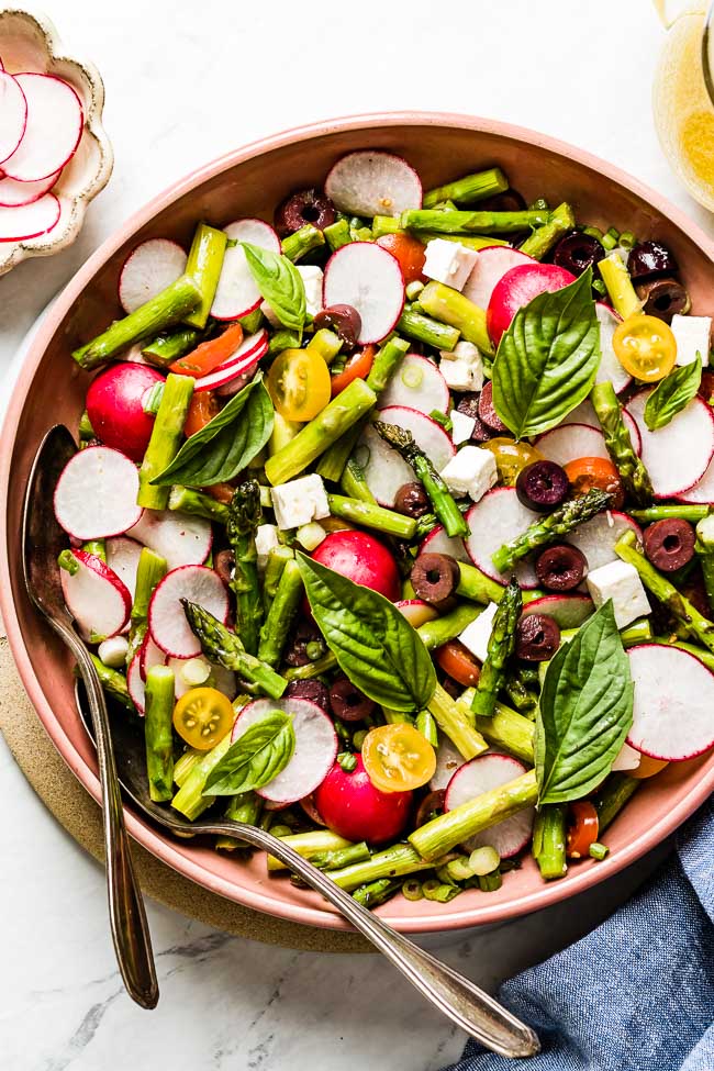 Asparagus Salad with Feta, Tomatoes and fresh basil in a large salad bowl from the top view.