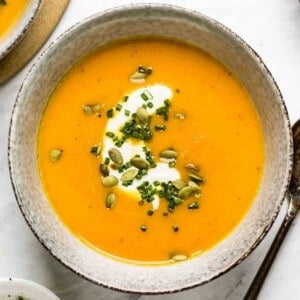 carrot soup with ginger served in a bowl garnished with pumpkin seeds