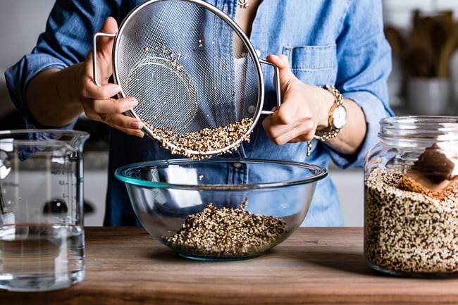 Person placing rinsed quinoa into a bowl from the front view.