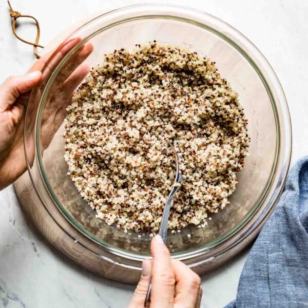 Microwave quinoa placed in a bowl and being fluffed by a woman