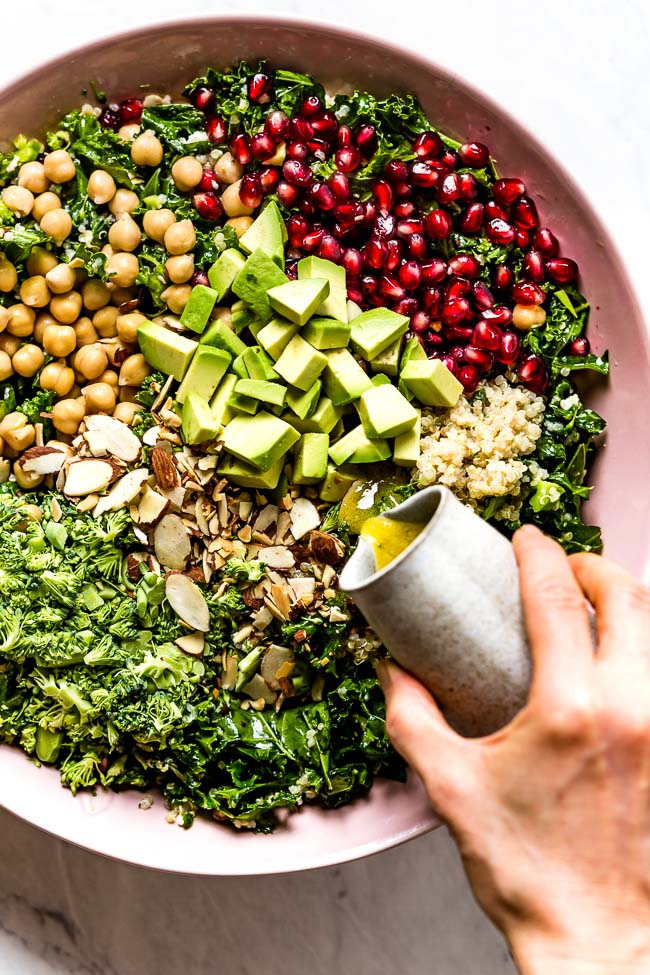 Quinoa Kale recipe being drizzled with lemon vinaigrette by a person