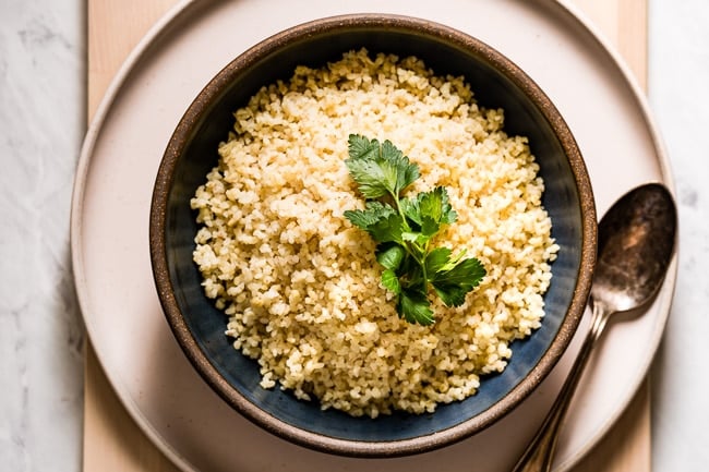 A bowl of cooked bulgur garnished with parsley