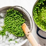 Placing blanched peas in a bowl with ice water