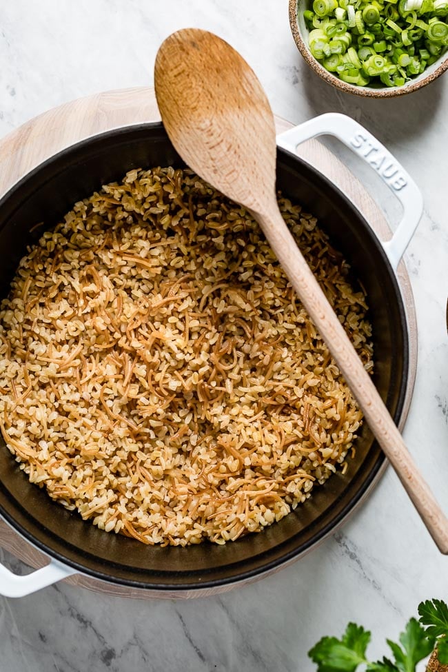 Bulgur with vermicelli in a dutch oven with a wooden spoon on the side