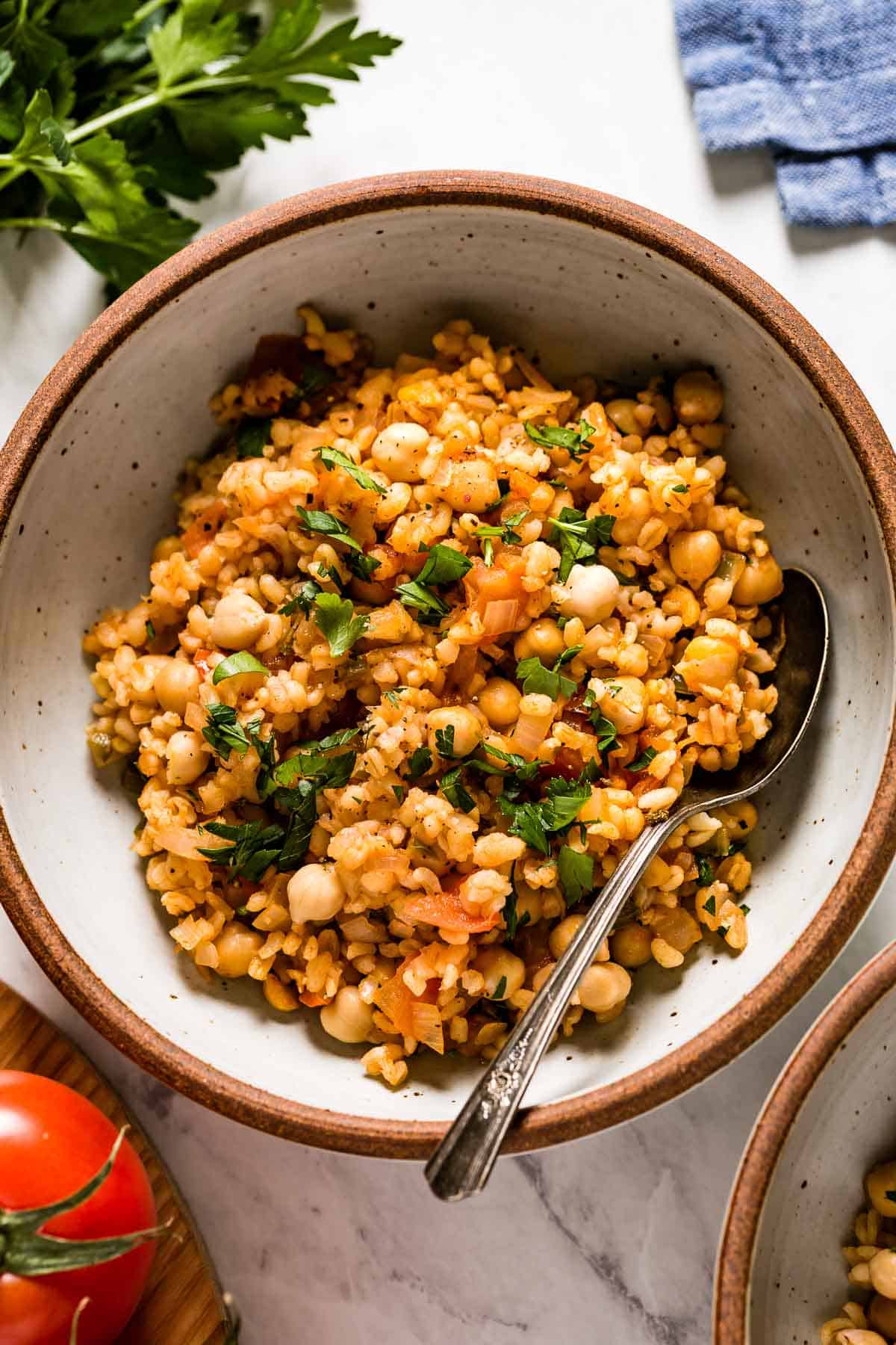 Bulgur pilaf in a bowl with a spoon on the side from top view.
