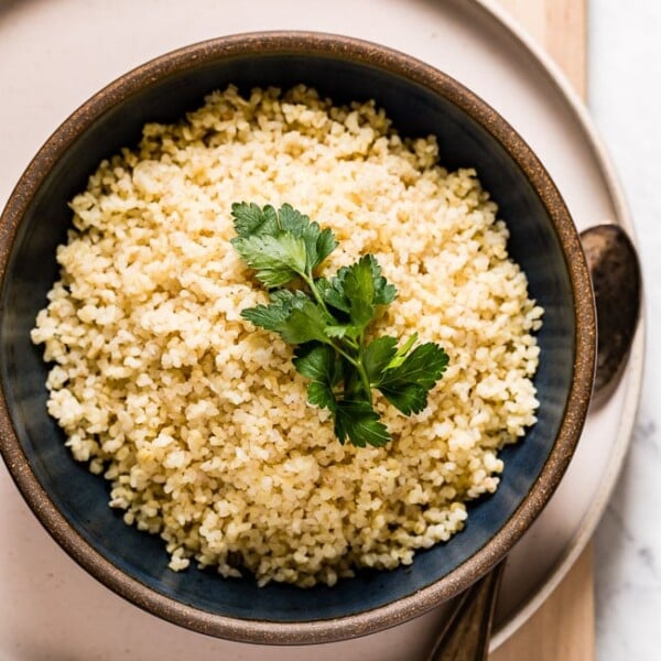 A bowl of cooked bulgur wheat in a bowl with a spoon on the side