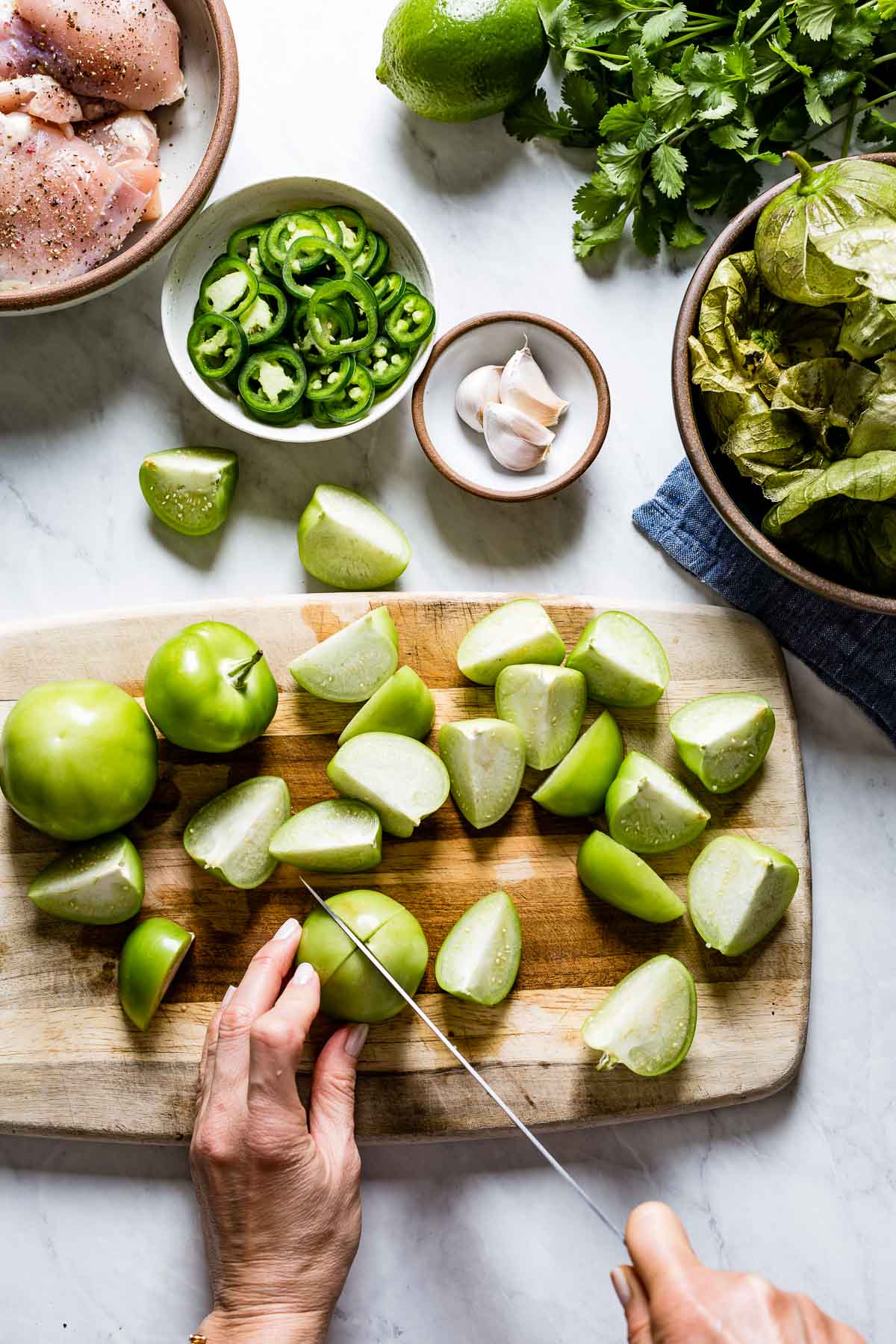 Person cutting tomatillos to make chicken soup