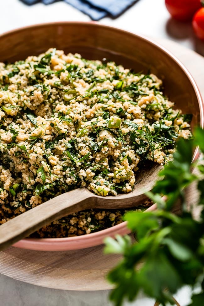 A bowl of Middle Eastern tabbouleh salad recipe in a bowl with a wooden spoon on the side.