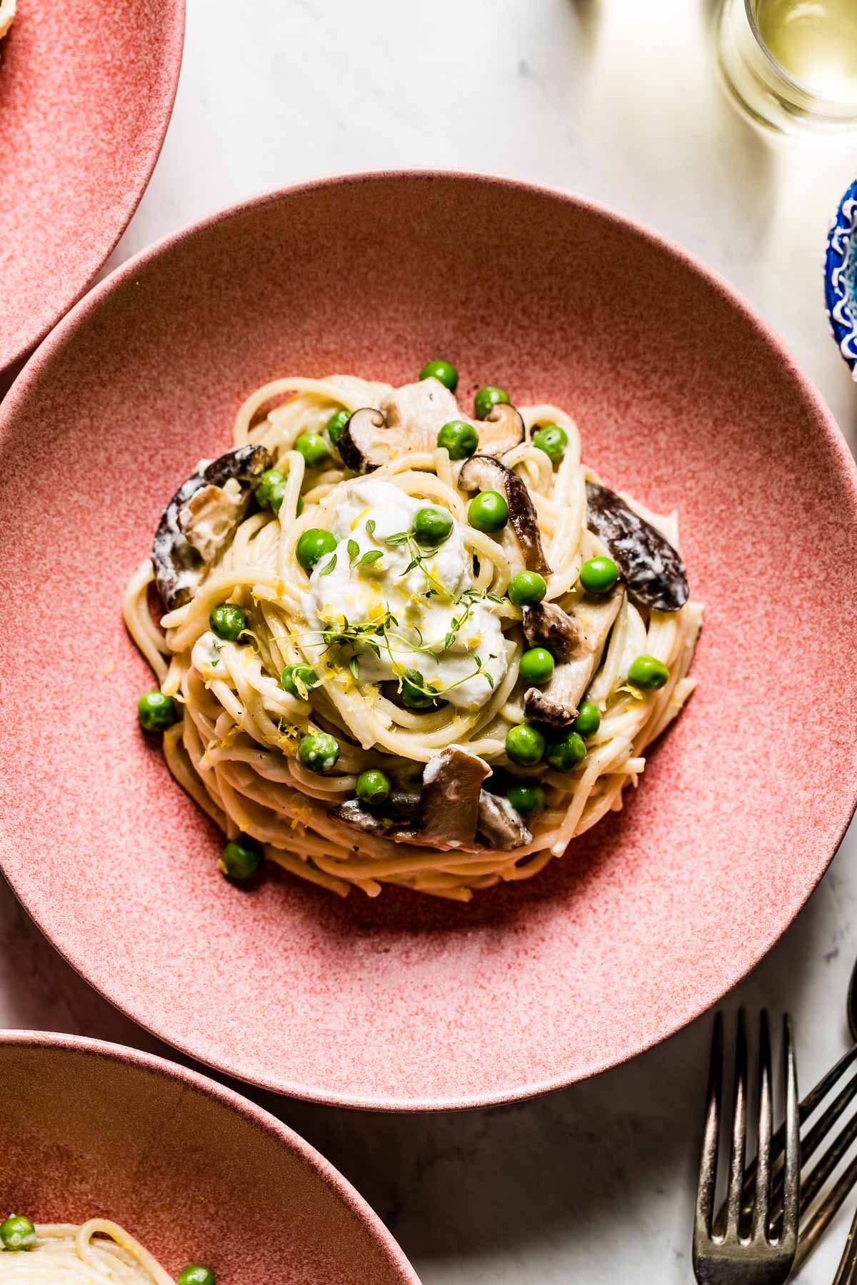 Pasta with mushrooms and peas in a bowl garnished with thyme.