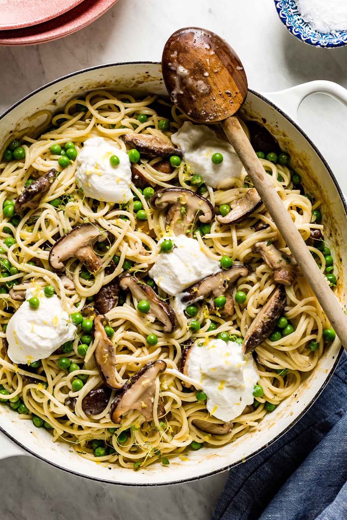 Creamy mushroom ricotta pasta in a skillet with a wooden spoon on the side