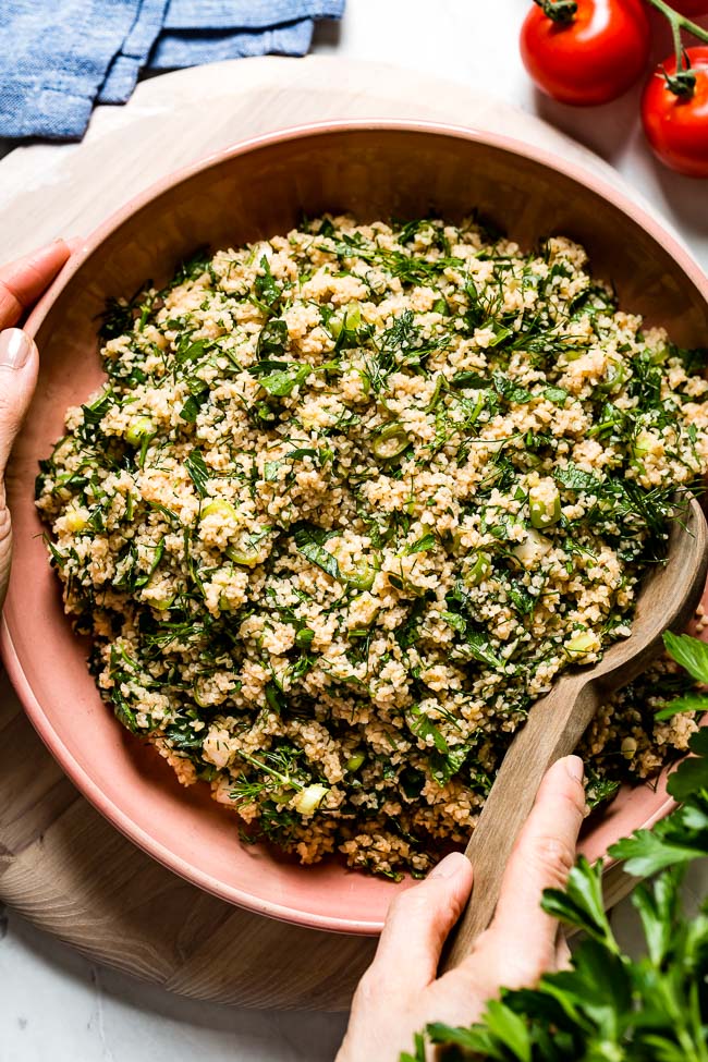 Tabbouleh salad served in a bowl by a person from top view