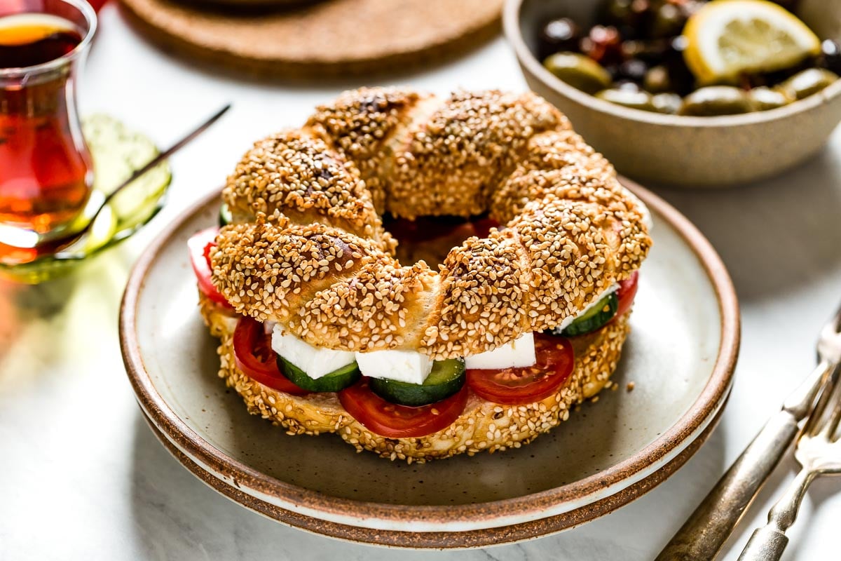 Simit sandwich on a plate layered with feta cheese and tomatoes