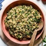 A bowl of tabbouleh from the top view with a wooden spoon on the side.