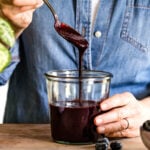 Blueberry Puree is placed in a jar by a person