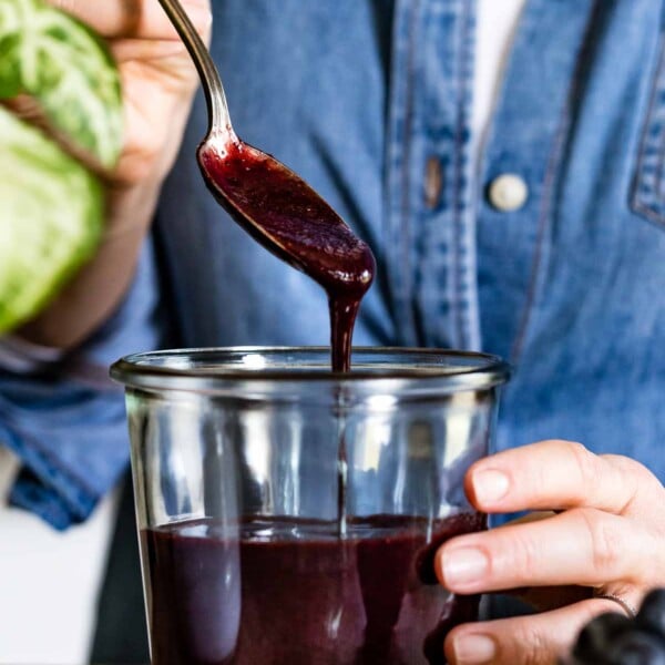 Blueberry puree is being placed in a jar by a person