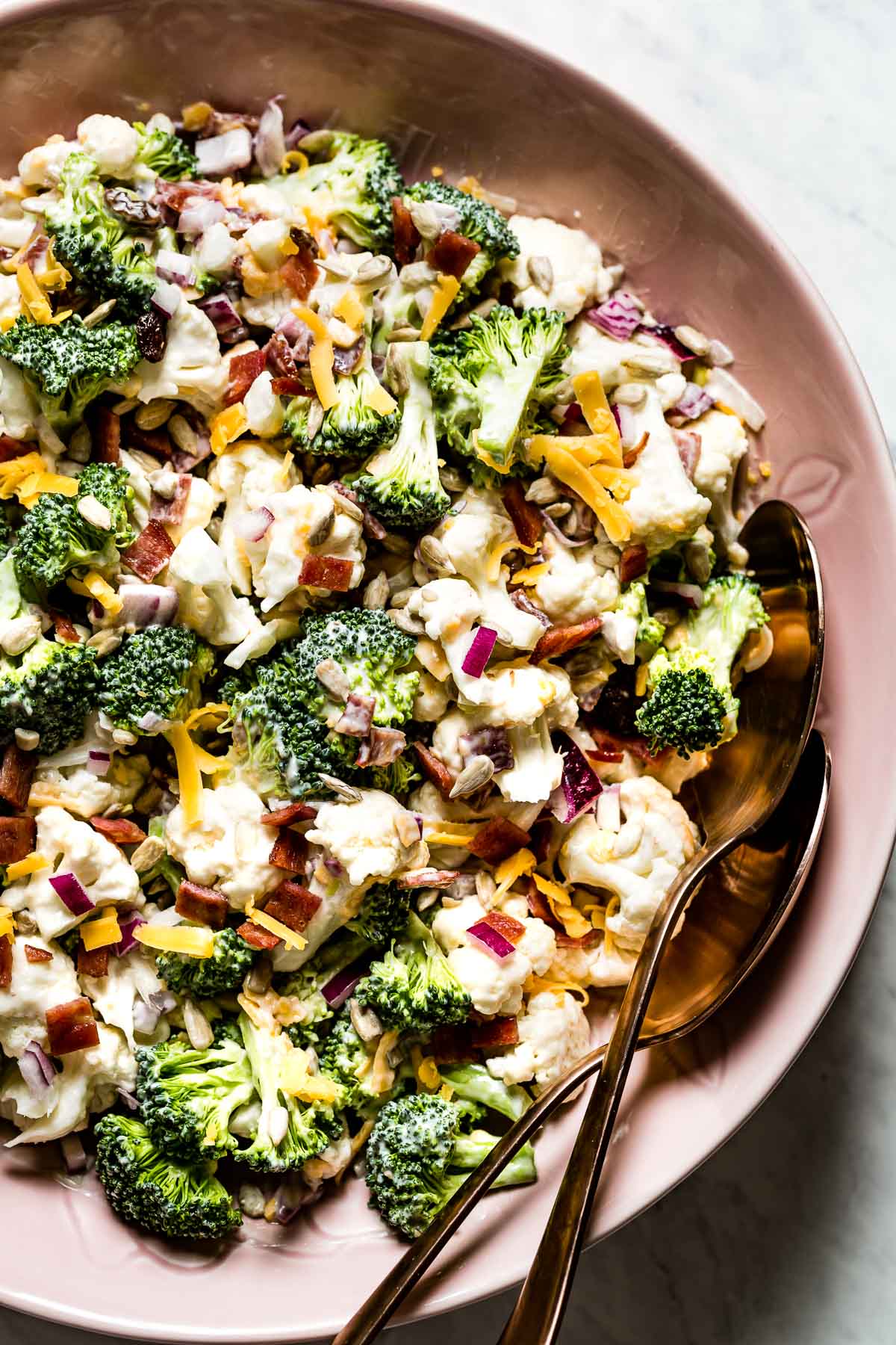 Broccoli Cauliflower Salad in a bowl with two spoons on the side top view.