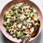 Broccoli & cauliflower salad in a bowl with two spoons on the side.