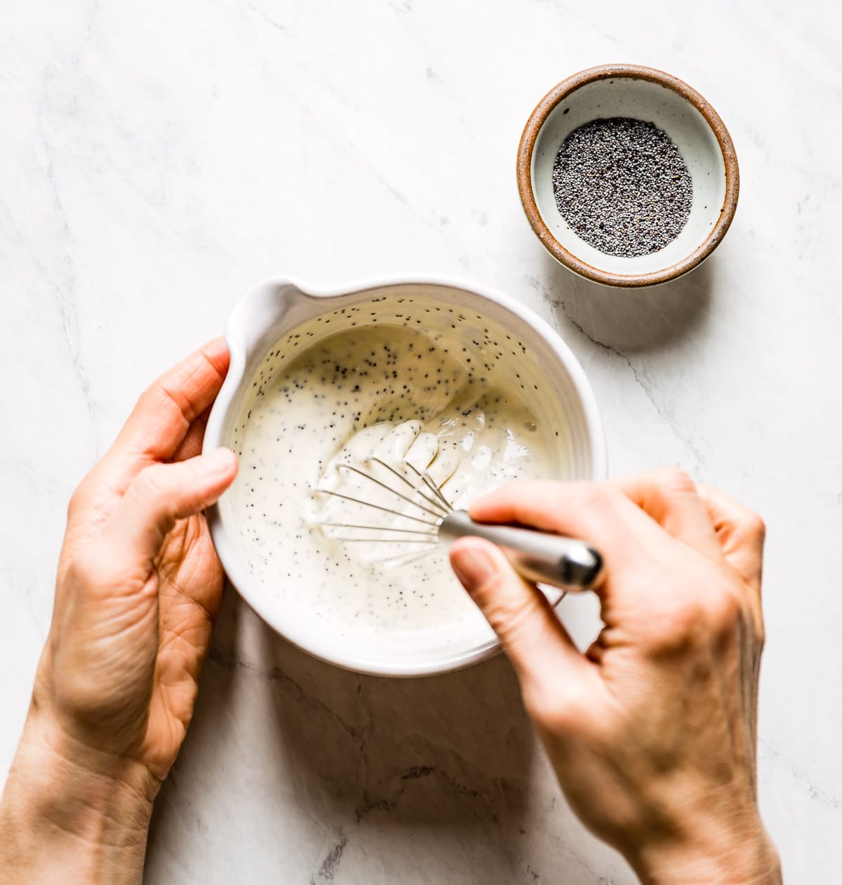 Person whisking poppy salad dressing with a whisk