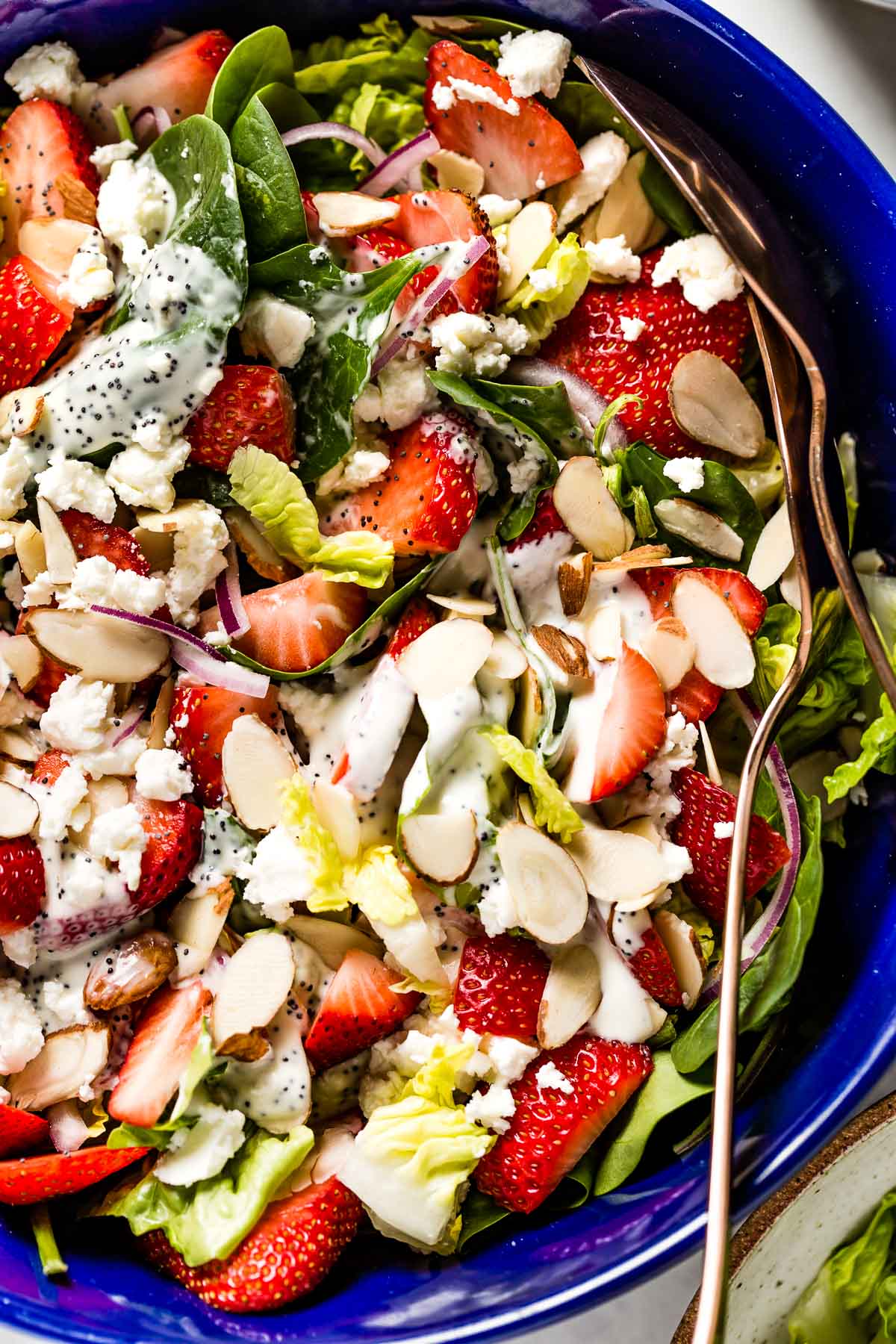 Strawberry Spinach Salad with Poppy Seed Dressing in a bowl with two spoons on the side