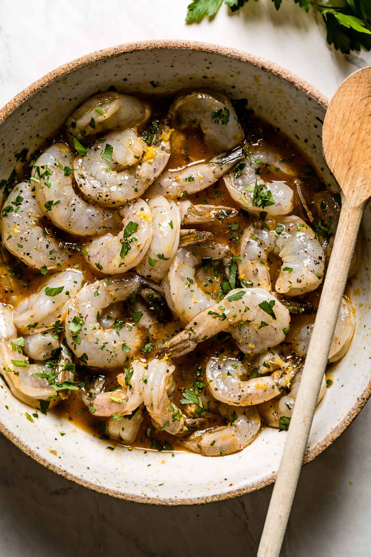 Grilled shrimp marinade in a bowl with a wooden spoon on the side