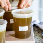Ina Garten's Chicken Stock in a container with a person in the background