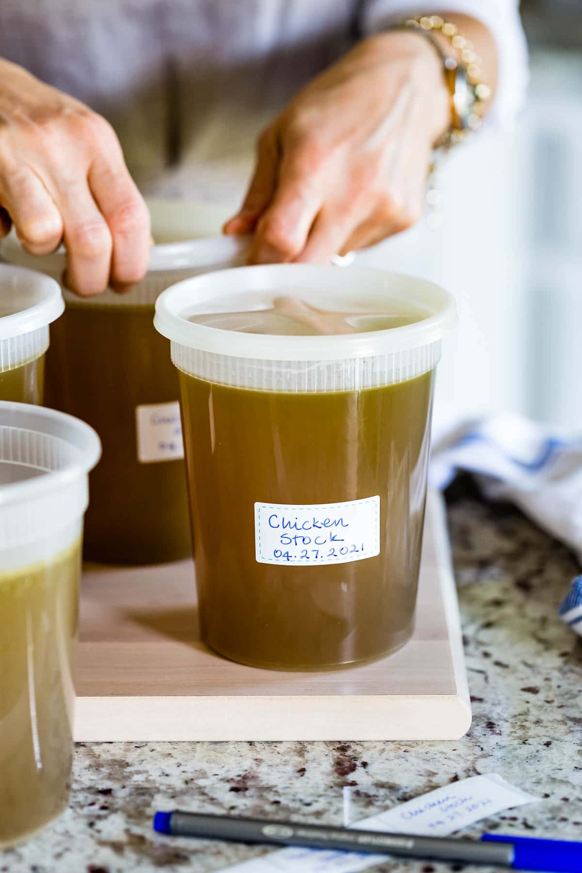 Chicken stock in a plastic container at the front with a person in the background