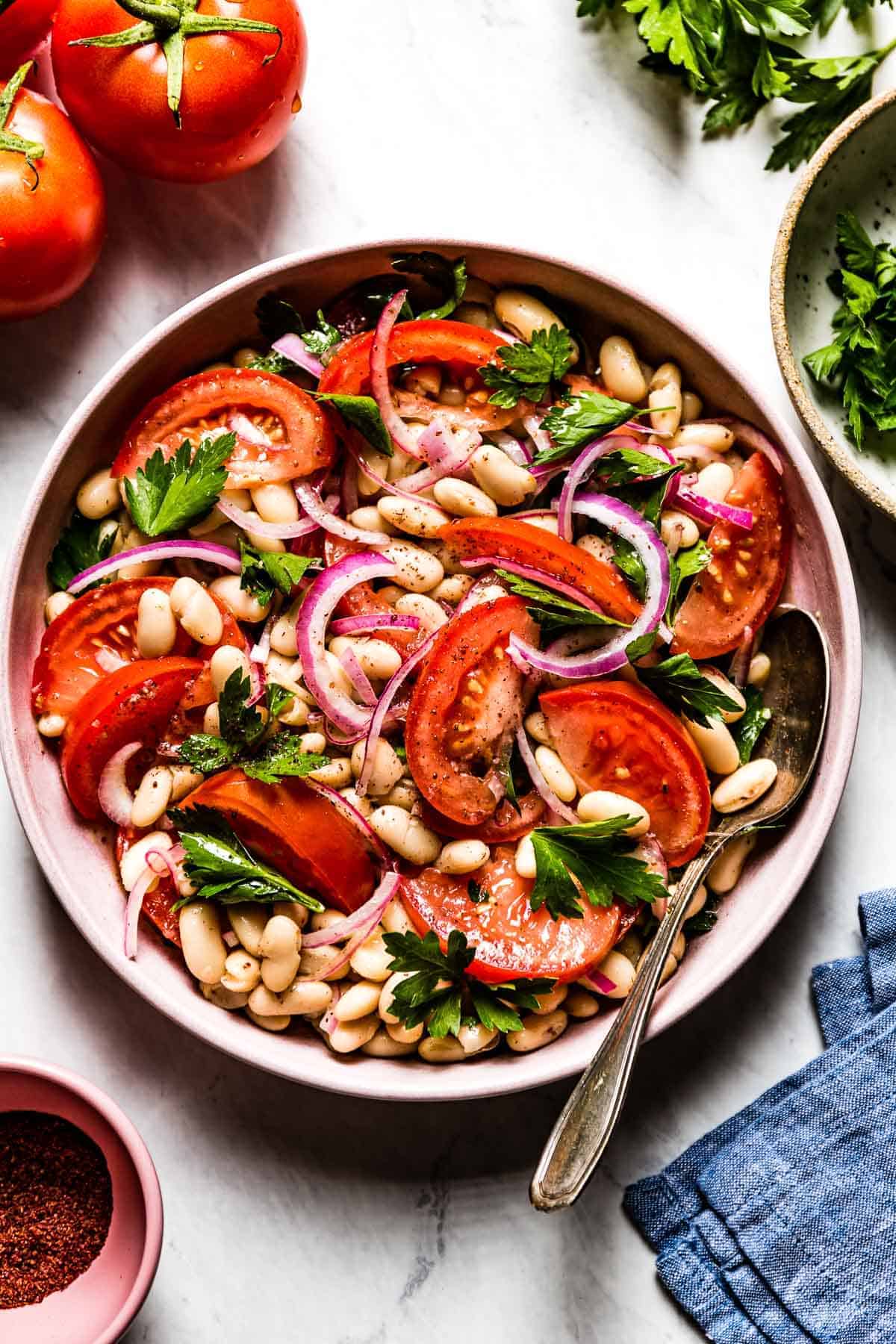 Piyaz - Turkish White Bean Salad in a bowl with a spoon on the side from top view.