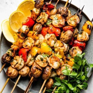 Grilled Shrimp Kabobs with Vegetables on a plate with herbs on the side
