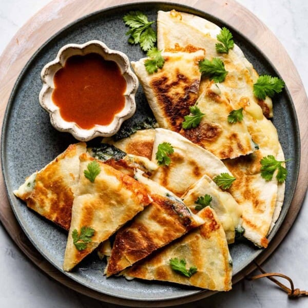 Spinach Quesadilla cut into small pieces served with sauce on the side
