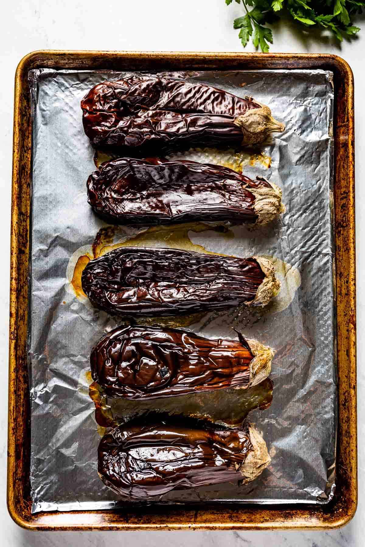 Whole roasted aubergine on a baking sheet from top view