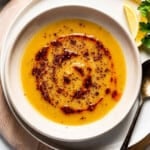 Turkish red lentil soup drizzled with chili oil in a bowl from the top view.