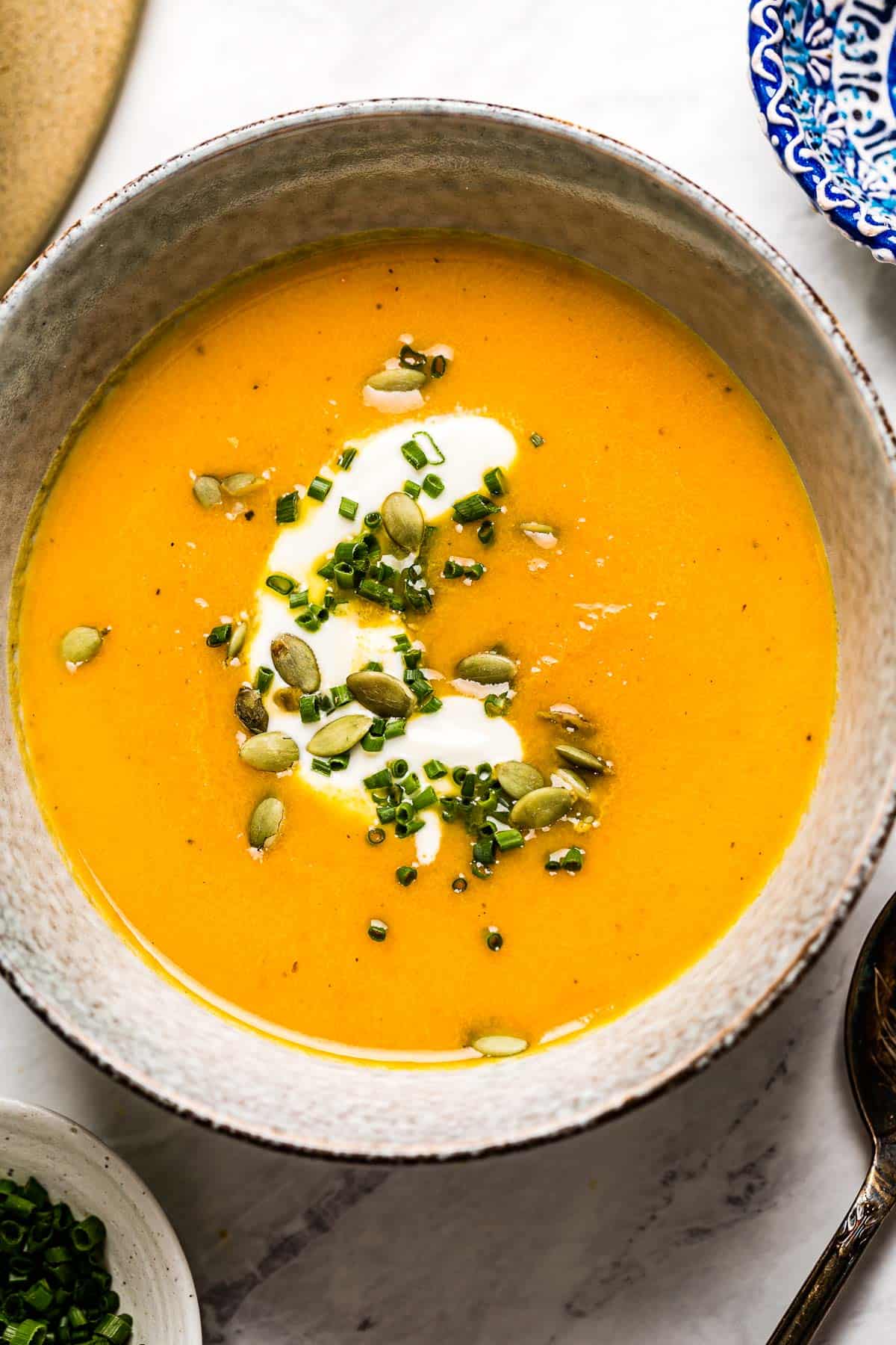 Healthy carrot ginger soup in a bowl garnished with creme fraiche