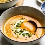 Carrot soup with ginger with a spoon in it.