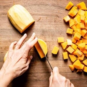 person cutting butternut squash into cubes