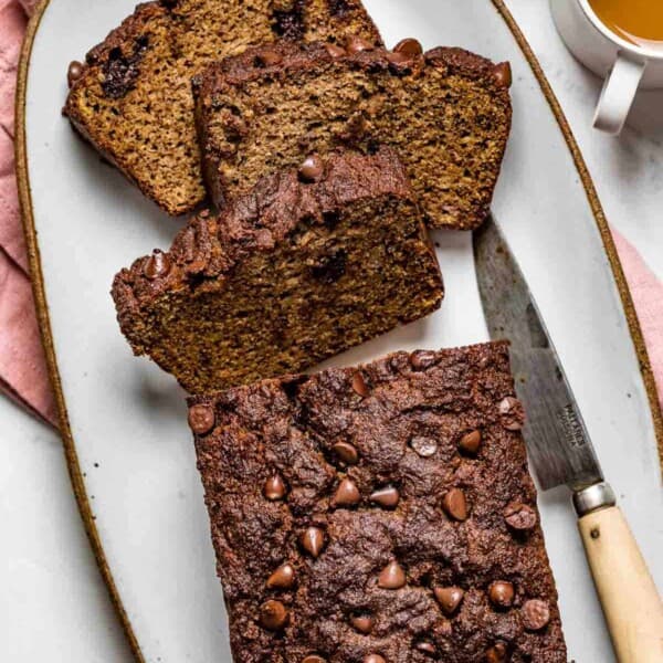 A few slices of almond flour banana bread on a plate with coffee on the side.
