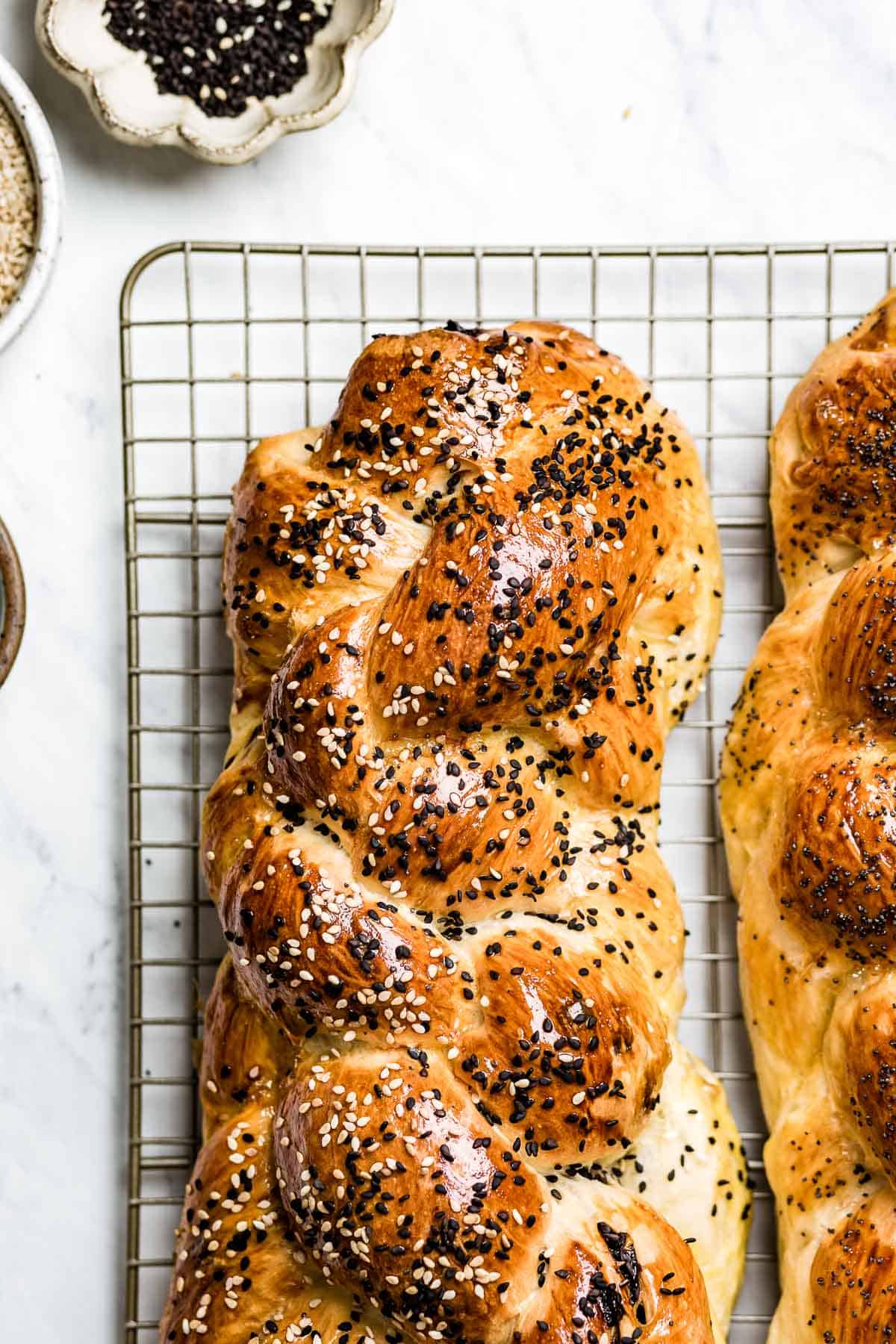 Challah loaf on a wire rack with toppings around
